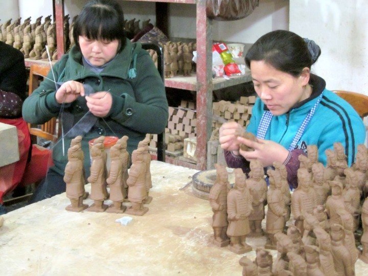 两个女人正在制作迷你兵马俑雕塑。