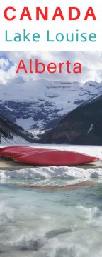 春天路易斯湖上的红色独木舟。冰雪覆盖的山脉和部分解冻的湖水-伟大的加拿大公路旅行冒险