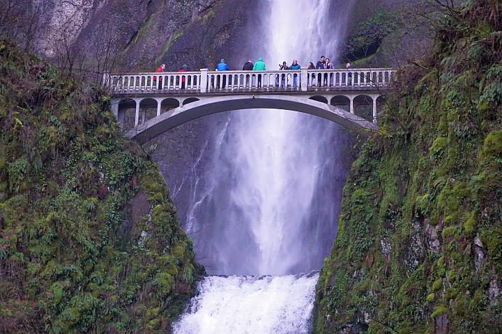 人们站在摩特诺玛瀑布对面的人行天桥上。