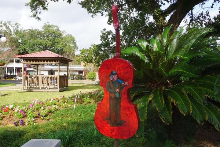 大型小提琴漆成红色，背面有一个小提琴手的形象，这是Opelousas LA小提琴狂热公共艺术的一部分
