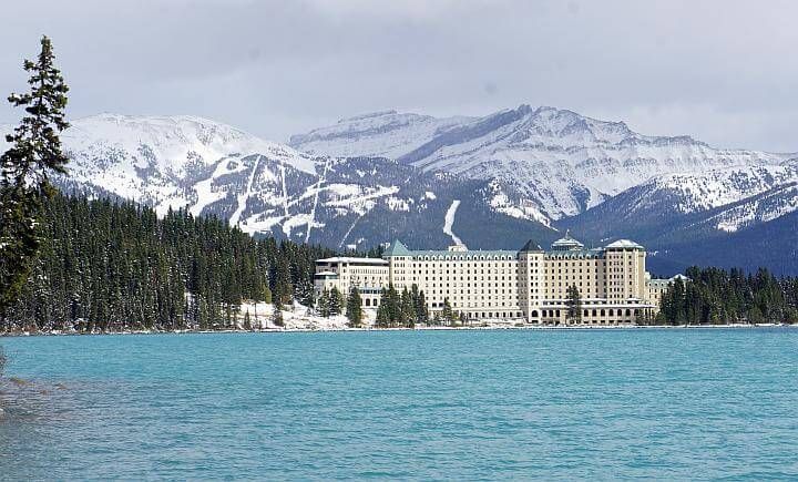 费尔蒙特路易丝湖城堡酒店从路易丝湖对面看，背景是白雪覆盖的山脉