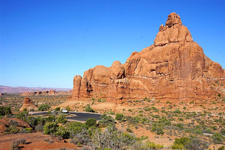 巨大的岩层和一辆汽车在蜿蜒的道路上的景观。