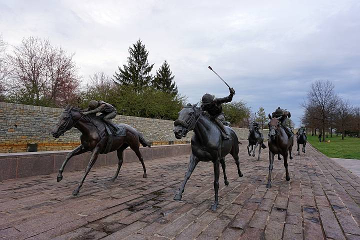 肯塔基州莱克星顿纯种马公园，真人大小的马匹雕像和骑师在赛道上比赛。