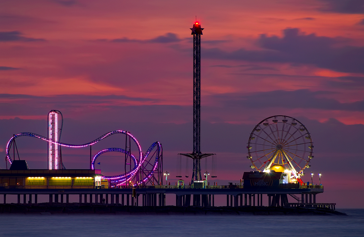 加尔维斯顿游乐码头、摩天轮和游乐园的游乐设施在晚上灯火通明。
