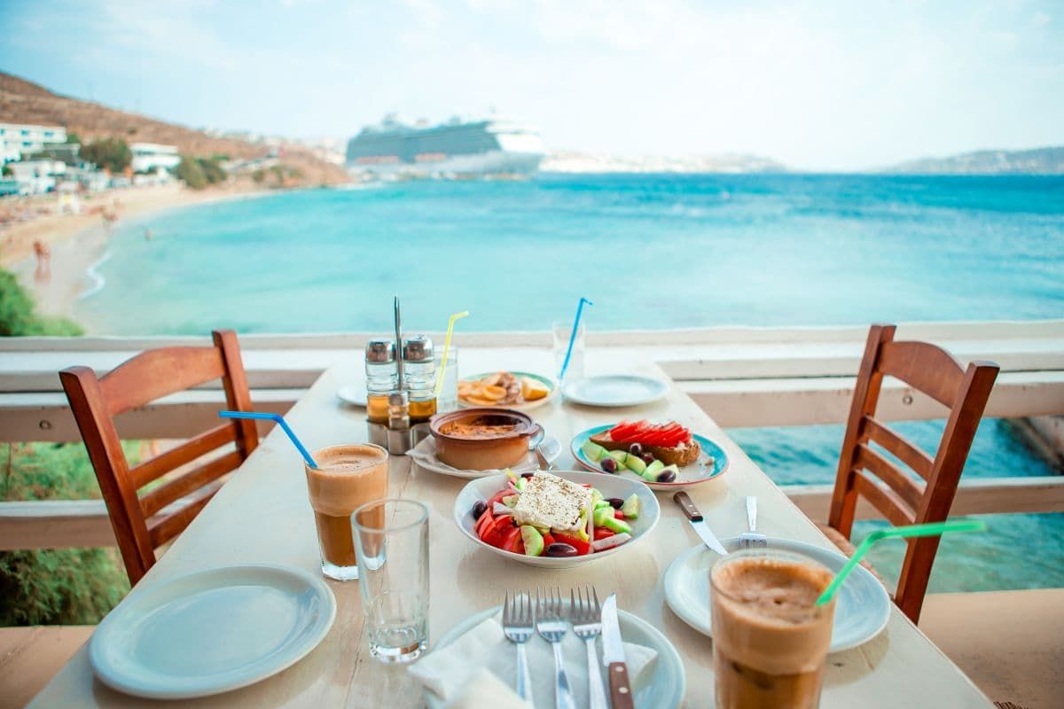 希腊户外餐桌设置共享菜肴，俯瞰大海。