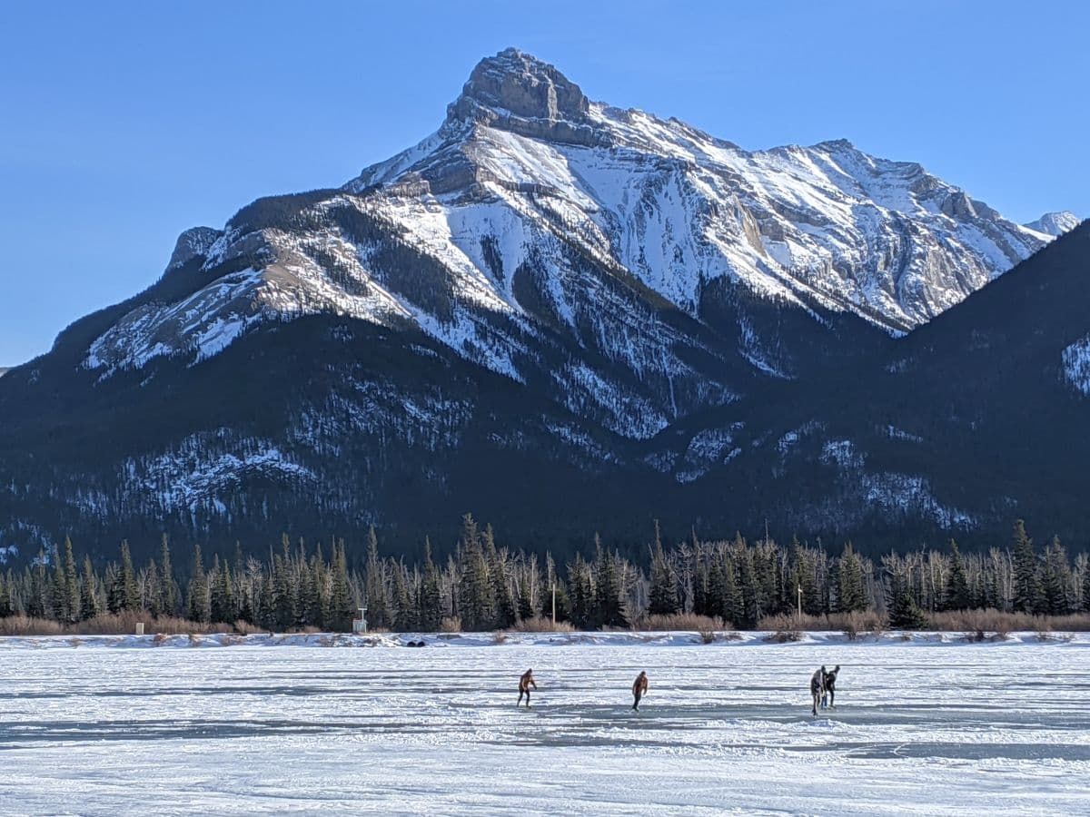 四人在坎莫尔野外滑冰，以山为背景。